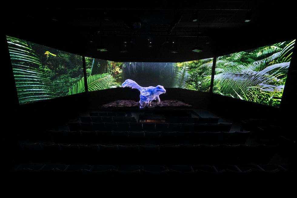 3D dinosaur in dark room with jungle screens in background.