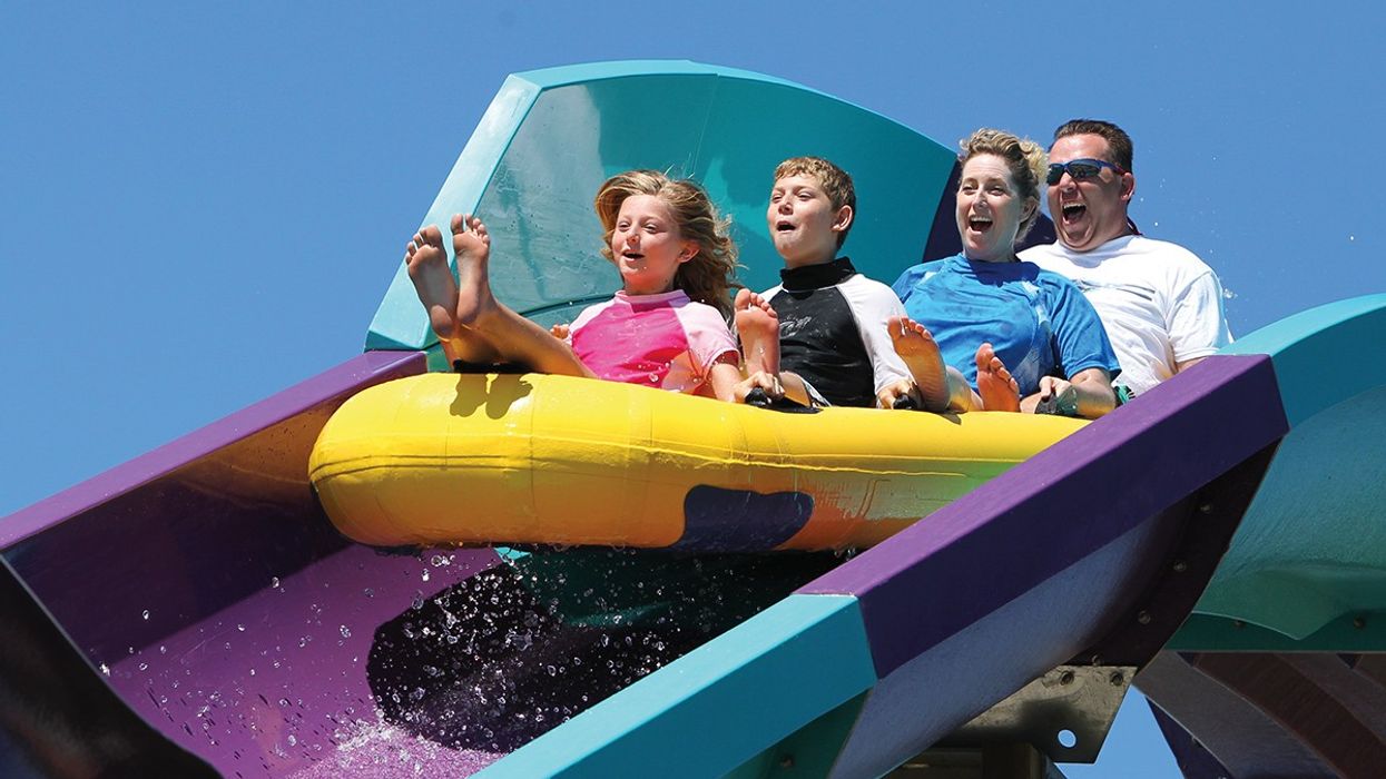 4 Passengers on a raft going down a purple and blue water coaster