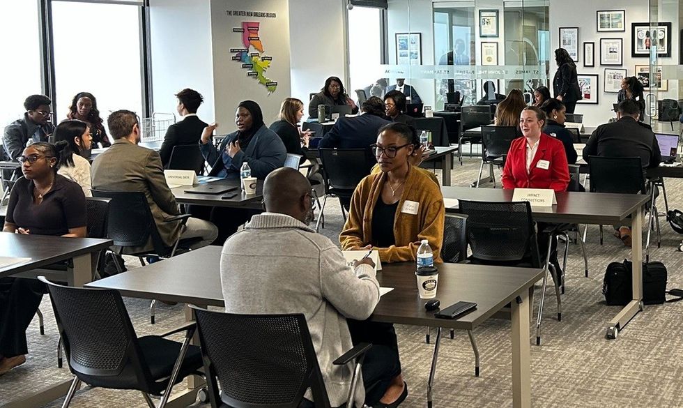 A busy office space with people engaged in interviews across several tables.