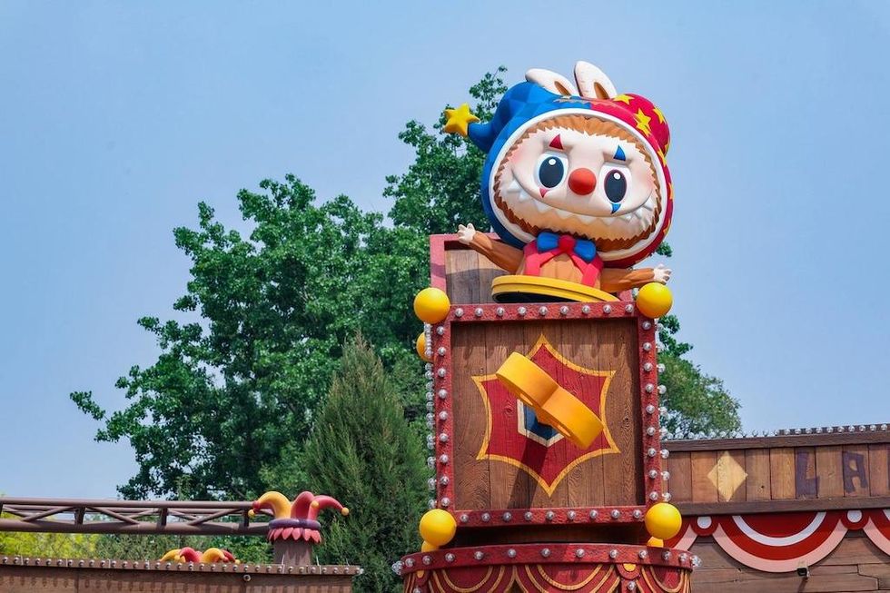 A colorful clown-like rabbit mascot stands atop a circus-themed wooden tower.