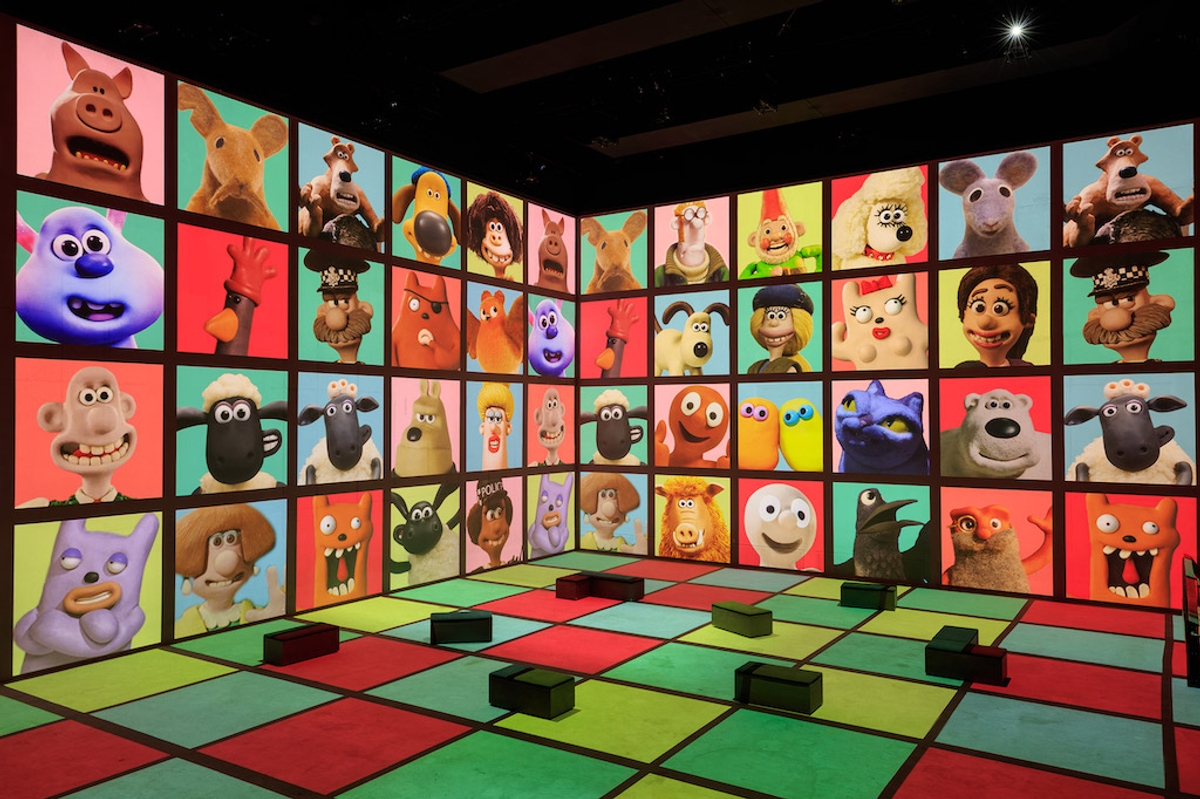 A colourful room featuring Aardman animated character faces projected on two walls