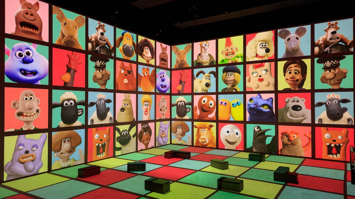 A colourful room featuring Aardman animated character faces projected on two walls