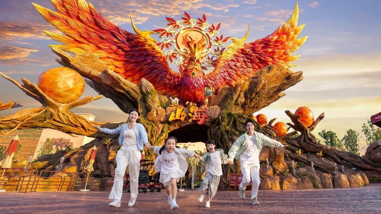 A family runs past a giant fiery phoenix sculpture at Ziyang Fantawild Oriental Legend Park.