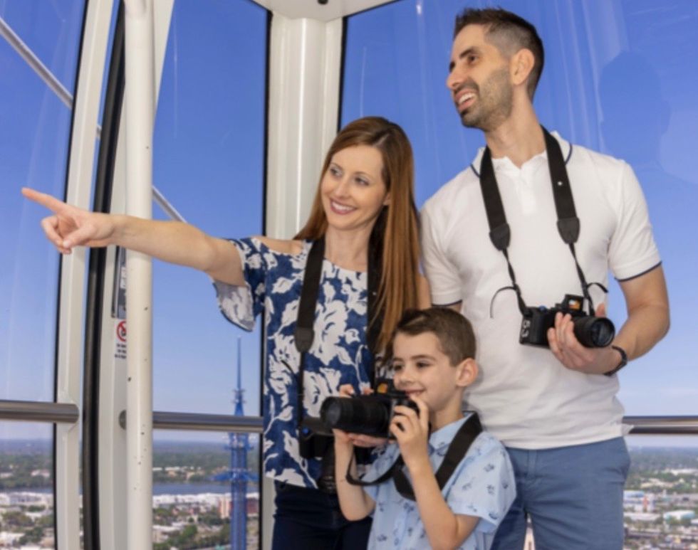 A family with Great Florida Road Trip camera devices on The Wheel at ICON Park