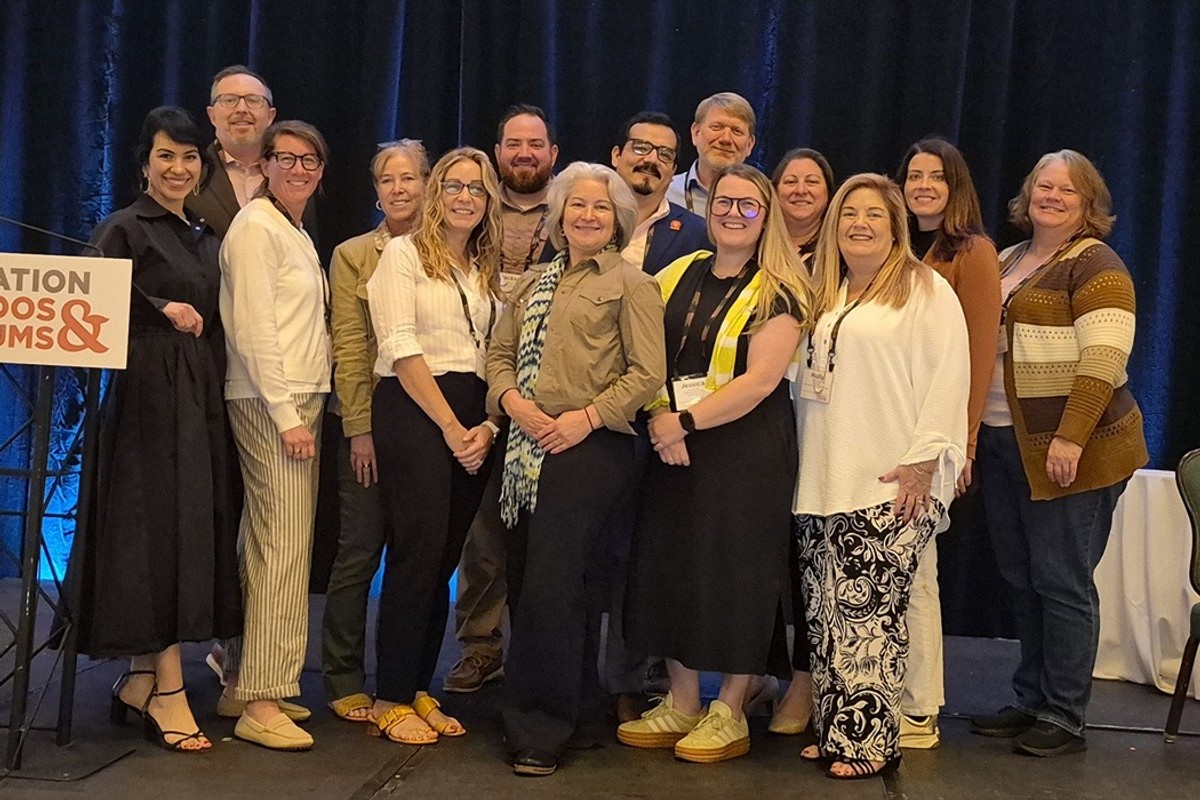 A group of people smiling on stage at a conference event.
