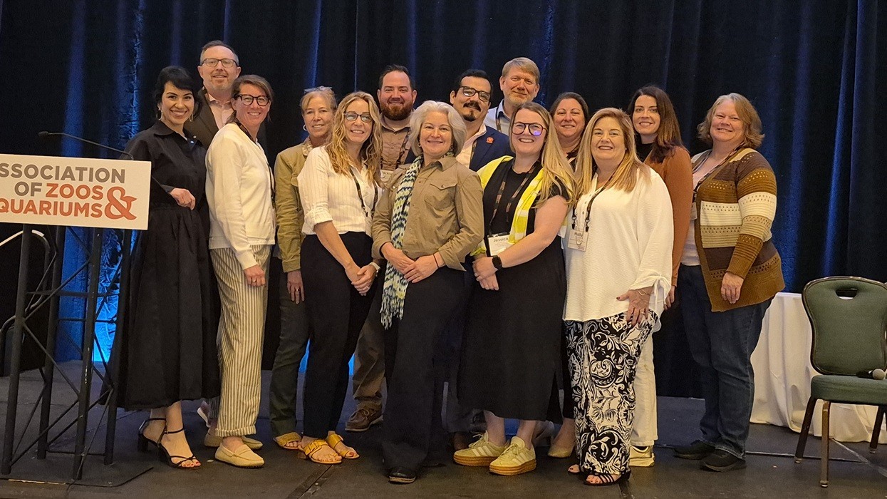 A group of people smiling on stage at a conference event.