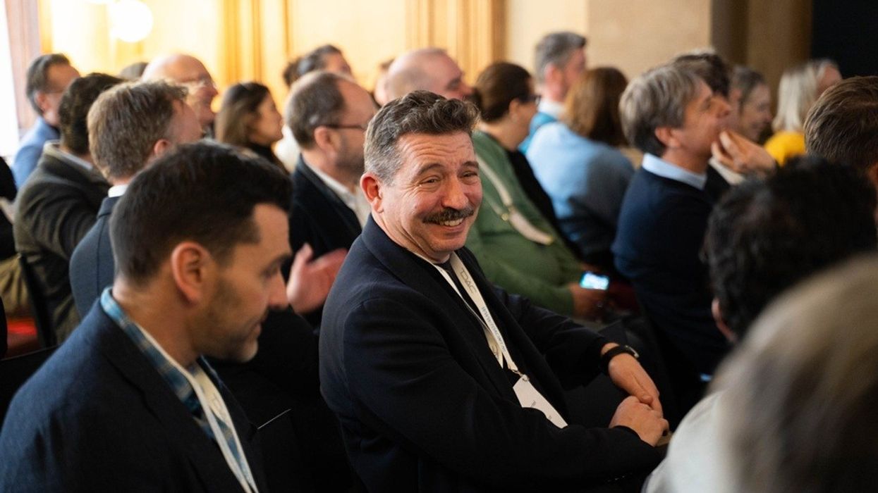 A man smiling at the 2025 Brand Experience Center Conference, seated among an attentive audience.