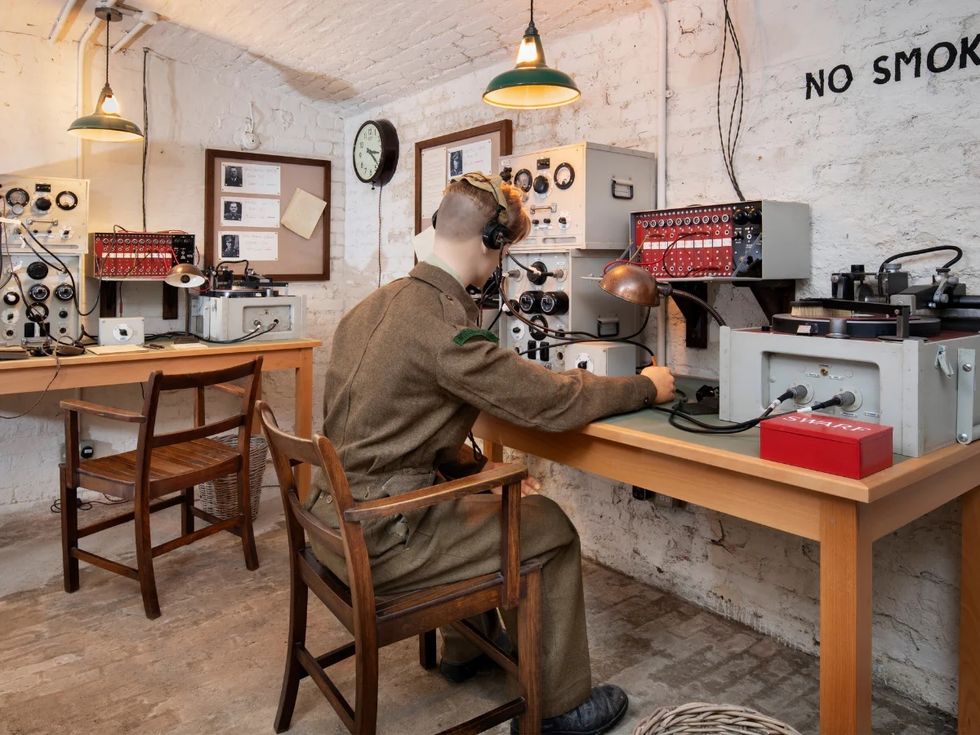 A mannequin in a vintage communication room with radios and equipment at Trent Park House of Secrets