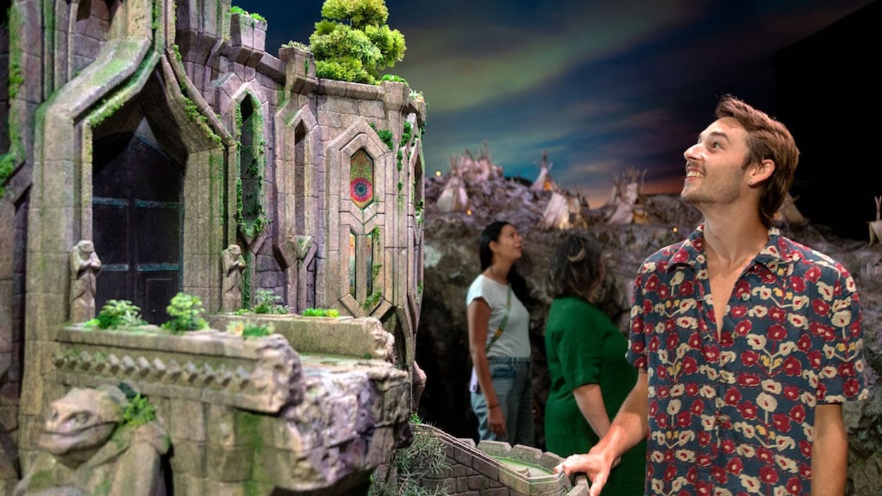 A person admiring a detailed, fantasy-like, miniature castle exhibit at Wētā Workshop Unleashed