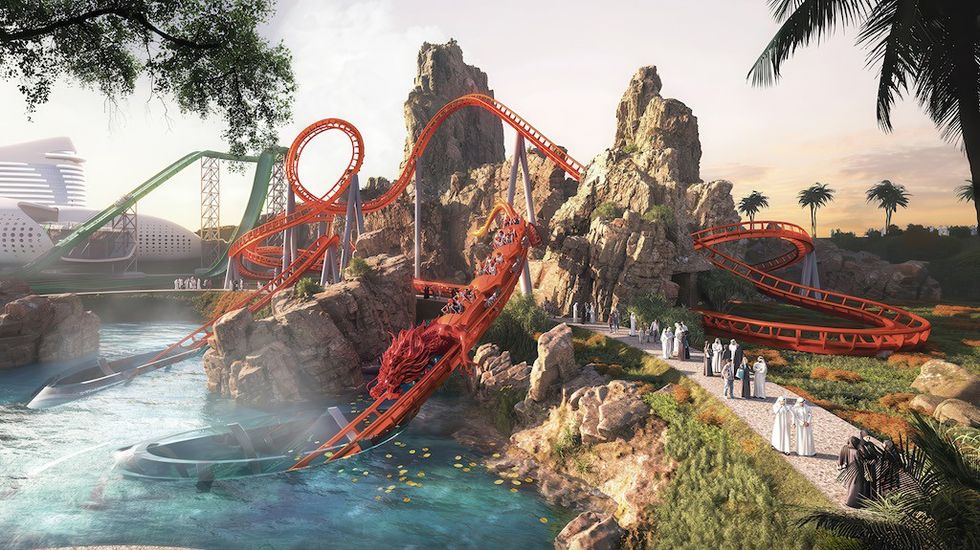 A red roller coaster winds through rocky terrain near water and palm trees.