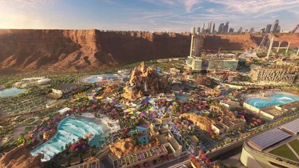 A vast desert cityscape with modern buildings and colorful waterparks under blue skies.
