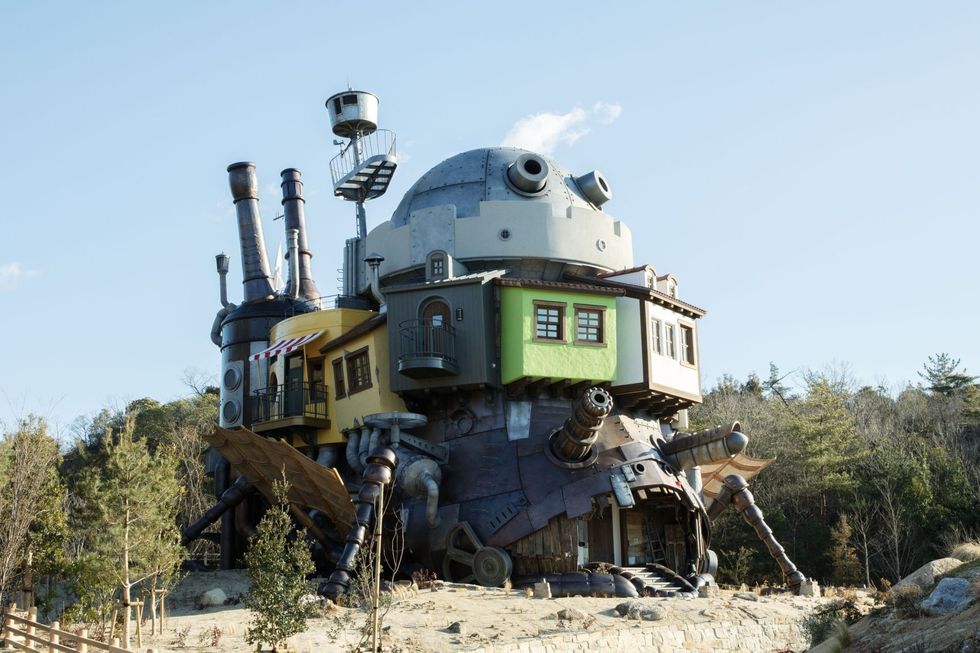 A whimsical, mechanical house with pipes and ladders set in a rural area.