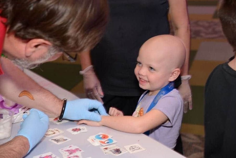 Adult putting a temporary tattoo on a child at Give Kids The World