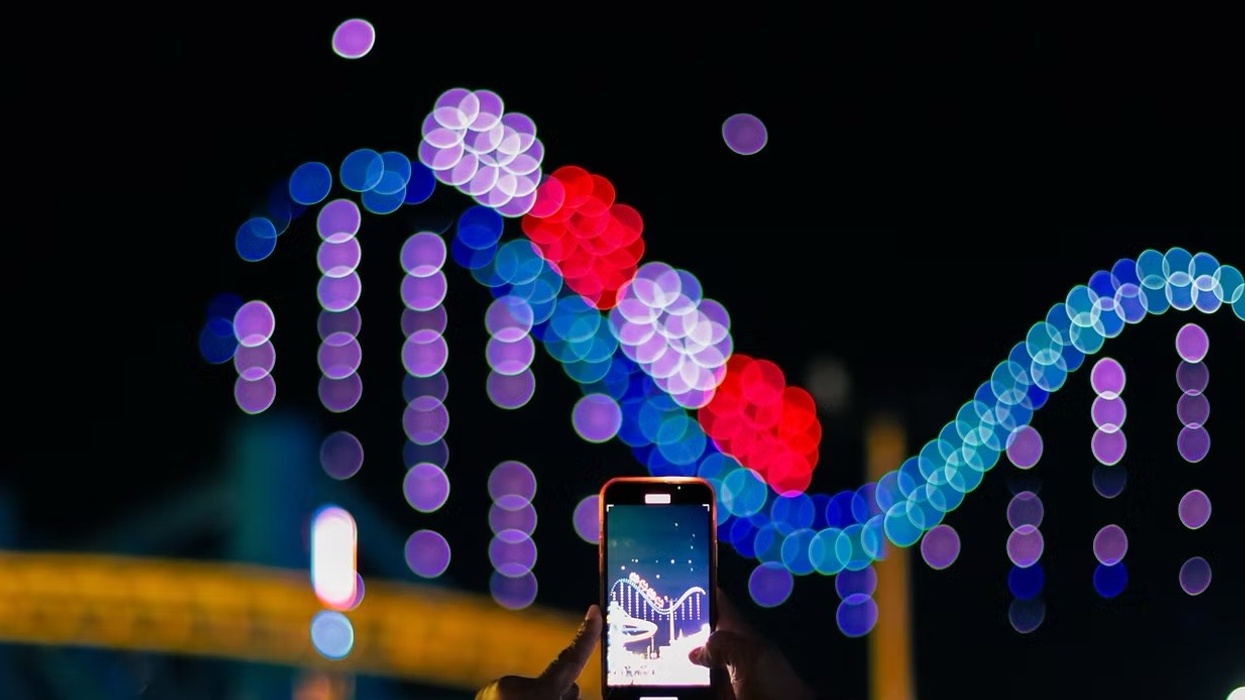 Aerial Illuminations drone show. The drones are forming the shape of a roller coaster drop. Some is recording the show on their phone.