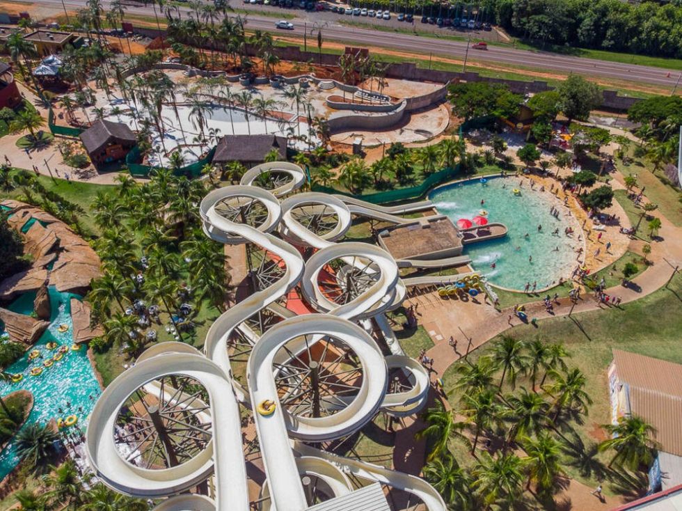 Aerial view of a bustling water park with twisting slides and palm trees at hot beach olimpia