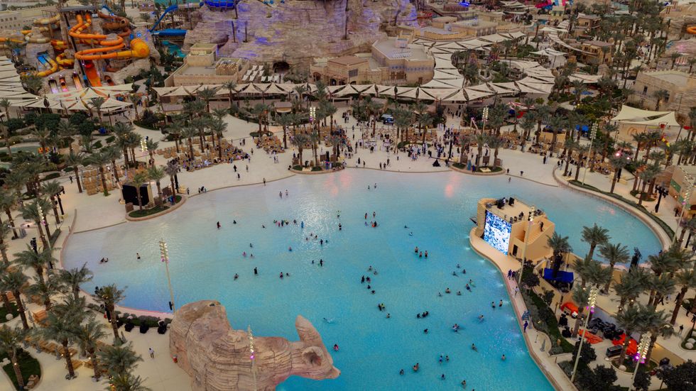 Aerial view of a busy water park called Aquarabia with a large pool and surrounding attractions.
