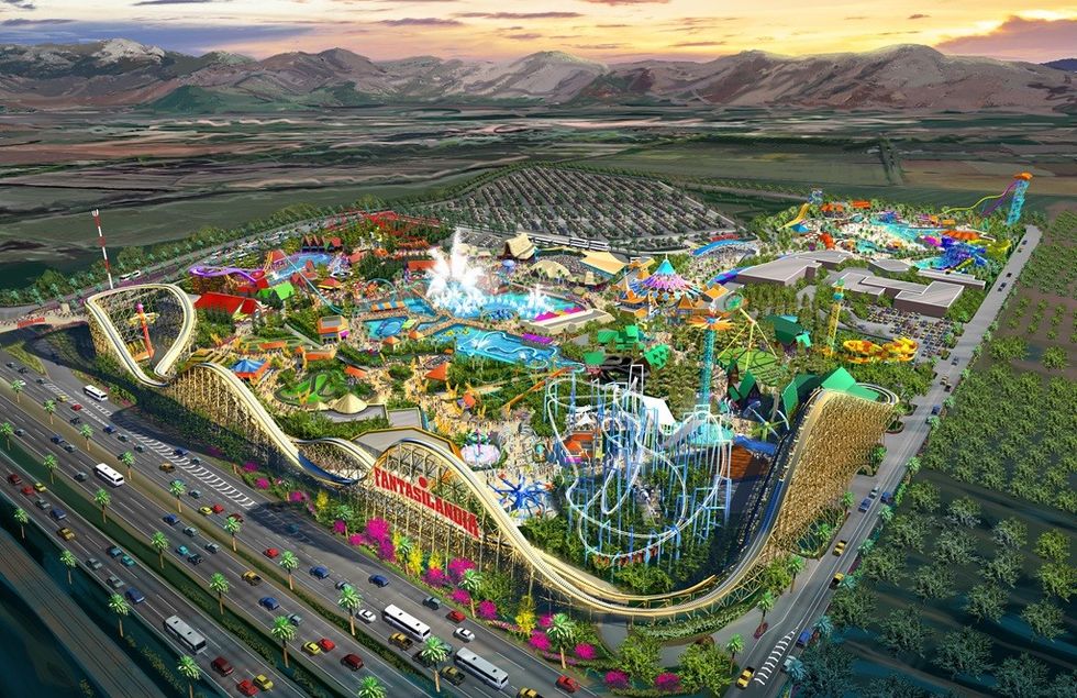 Aerial view of a colorful amusement park called Fantasilandia with roller coasters and a large parking area.