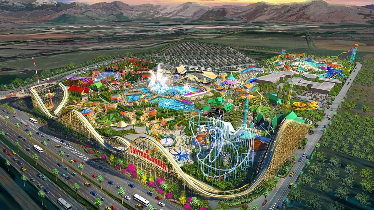 Aerial view of a colorful amusement park with roller coasters and a large parking area.