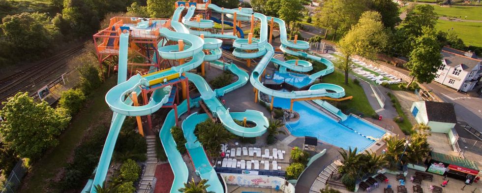 Aerial view of a colorful, twisting water park with slides and trees in the background, Splashdown Quaywest
