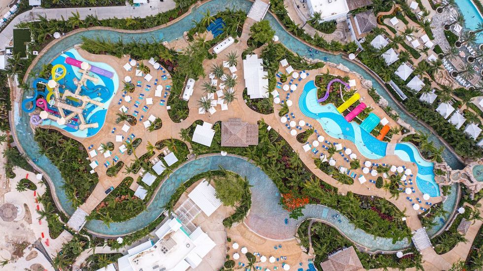 Aerial view of a colorful water park with pools, slides, and surrounding greenery.