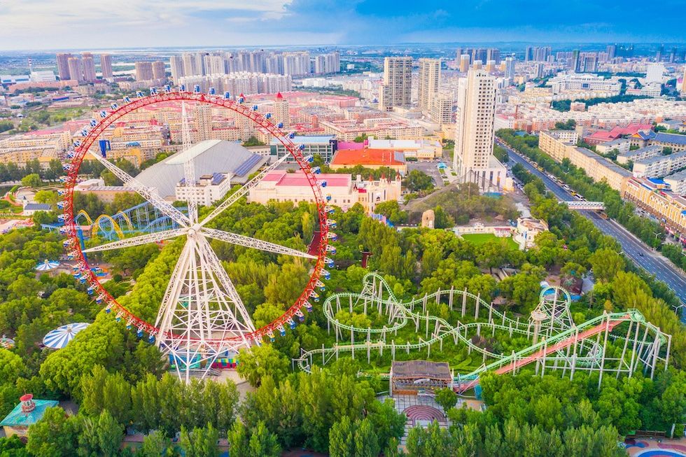 Aerial view of a Ferris wheel and roller coaster in a city amusement park.