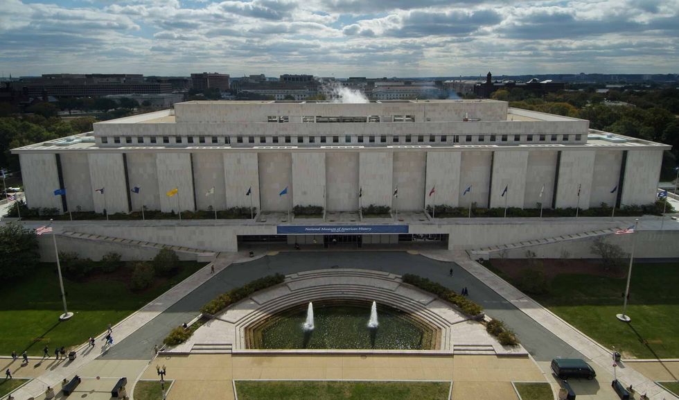 Aerial view of a large, rectangular government building, National Museum of American History, with a fountain in front.