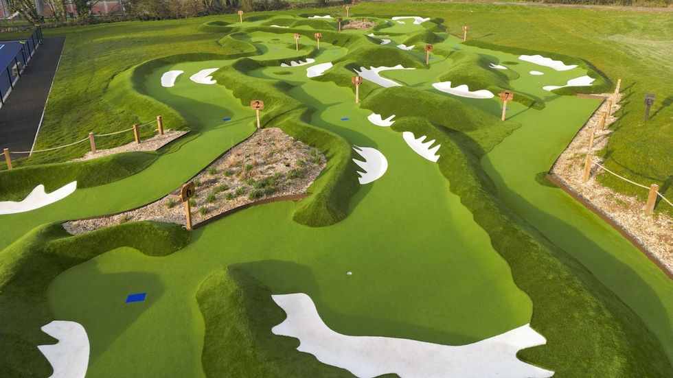 Aerial view of a lush, undulating mini-golf course with numbered holes and paths.
