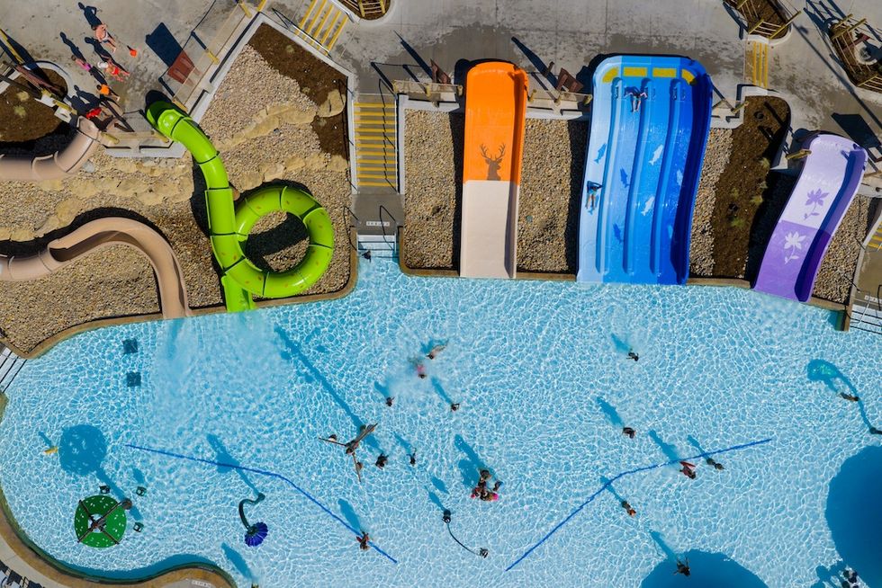 Aerial view of a pool with colorful water slides and people swimming.