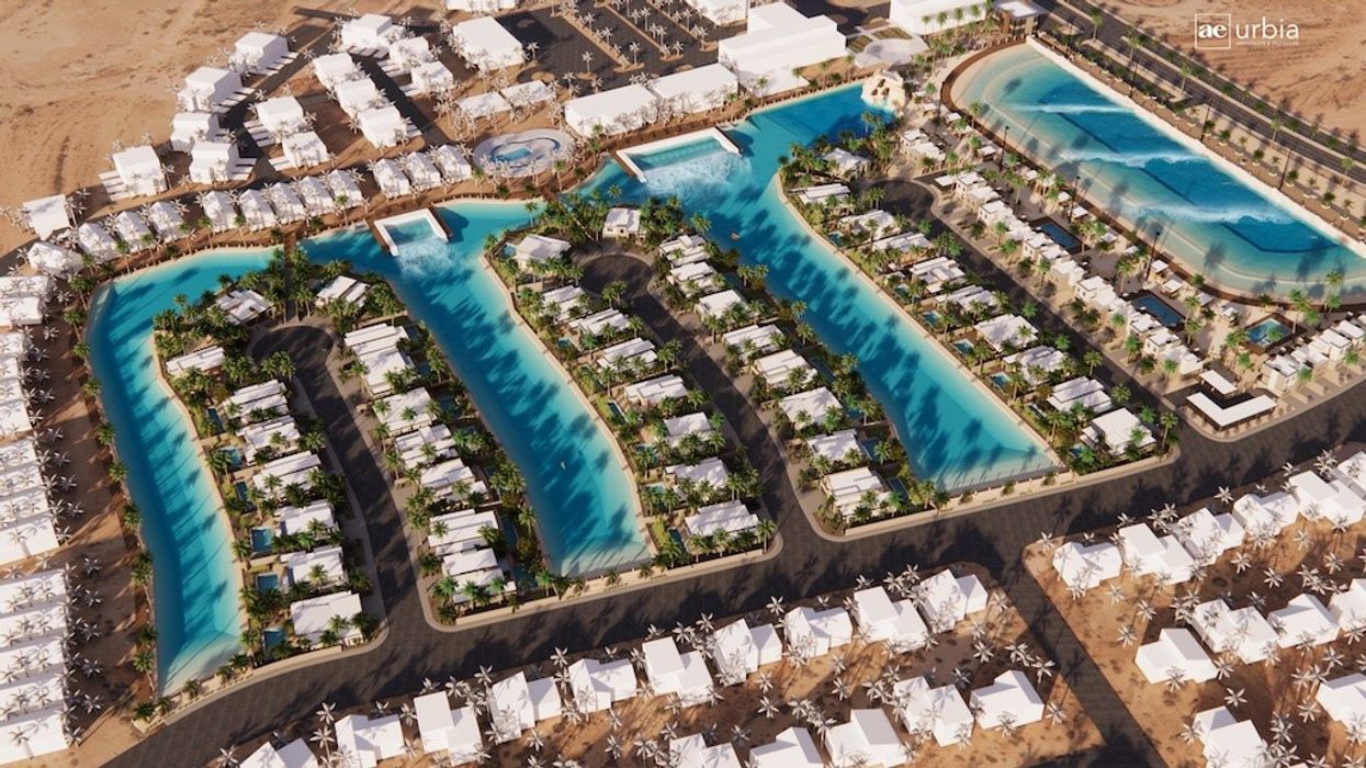 Aerial view of a resort with pools, palm trees, and white-roofed buildings in a desert setting.