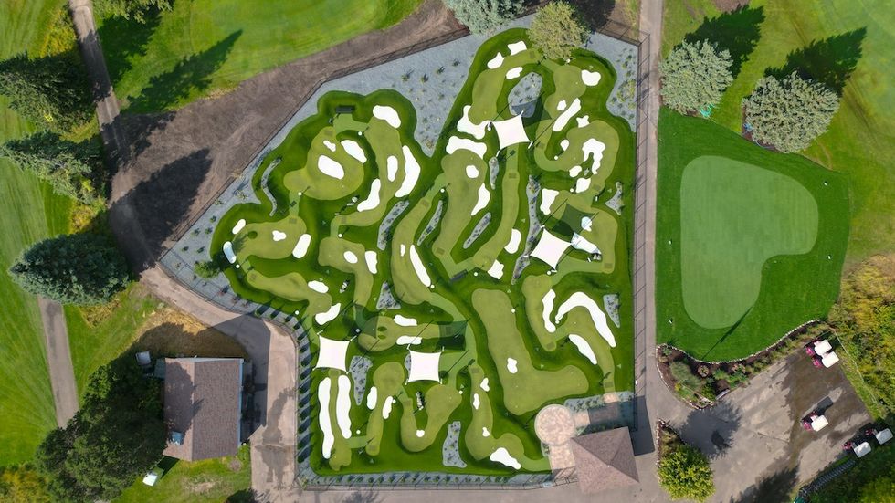 Aerial view of a small, intricate mini-golf course with white sand traps and green fairways.