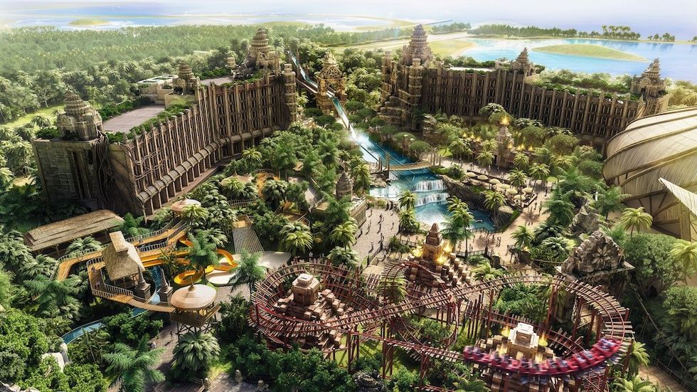 Aerial view of a tropical theme park with roller coasters and lush greenery.
