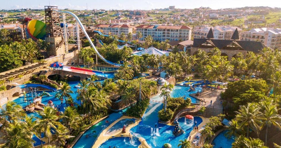 Aerial view of a tropical water park called Beach Park with slides and lush greenery.