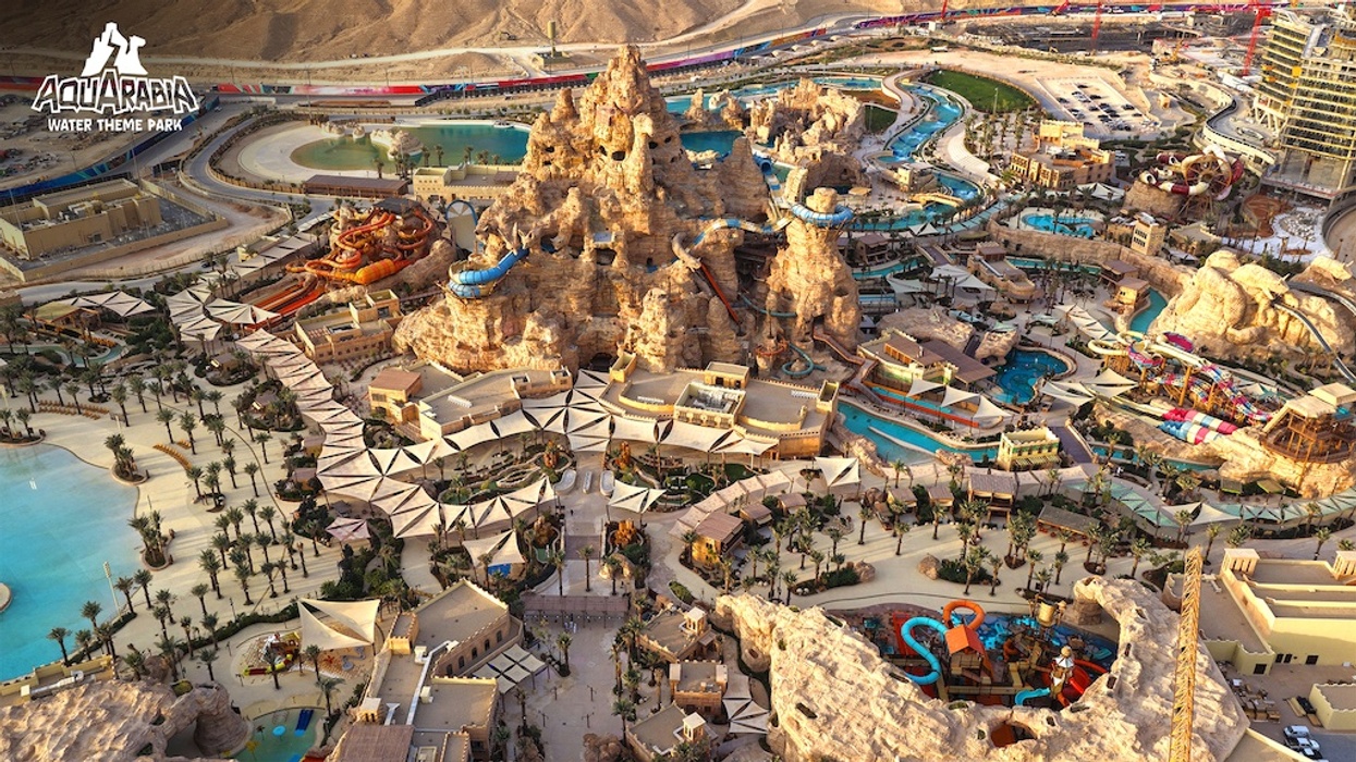 Aerial view of a vast, colorful water theme park with slides and pools in a desert landscape.