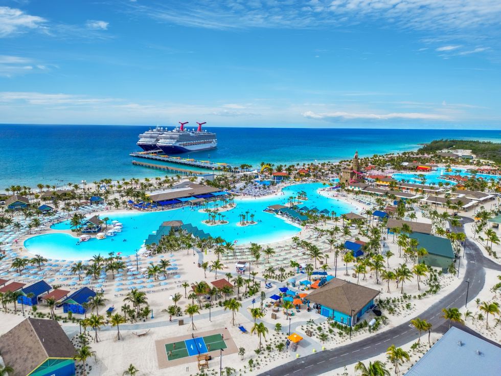 Aerial view of a vibrant beachfront resort with pools and a cruise ship docked nearby.