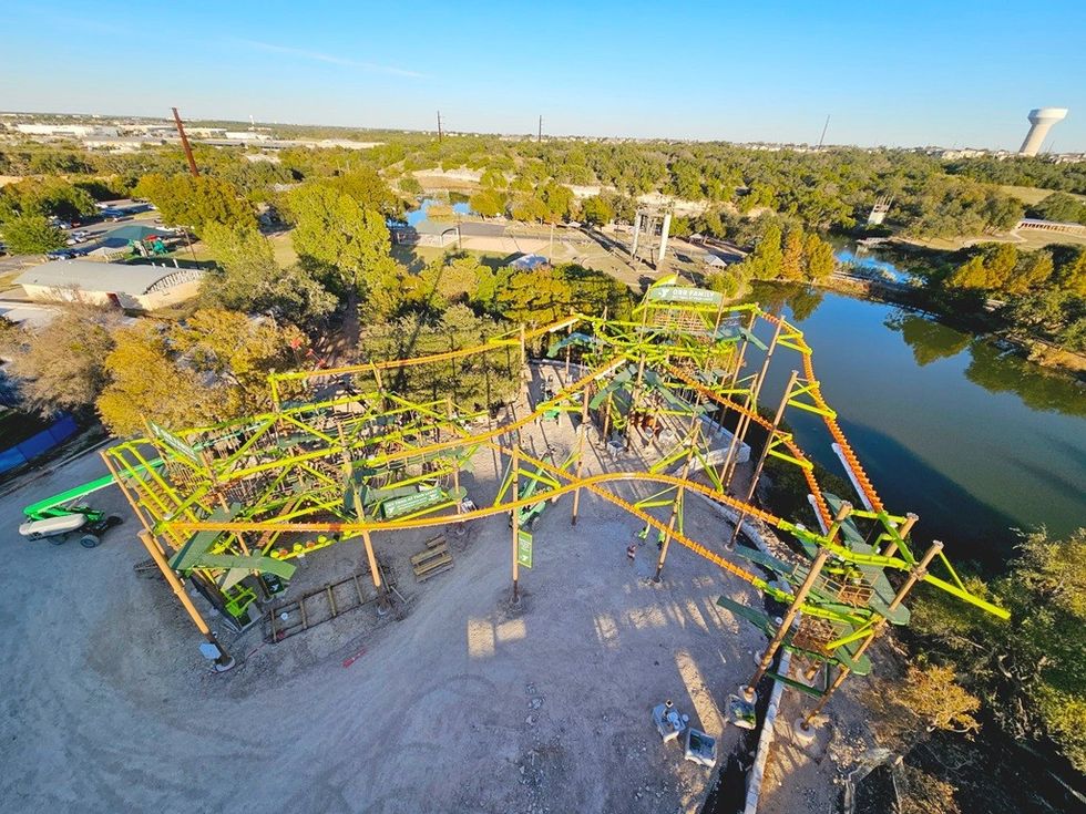 Aerial view of a vibrant outdoor ropes course near a lake, surrounded by trees.
