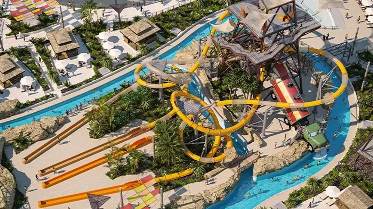 Aerial view of a water park with colorful slides and lazy river amidst tropical scenery.