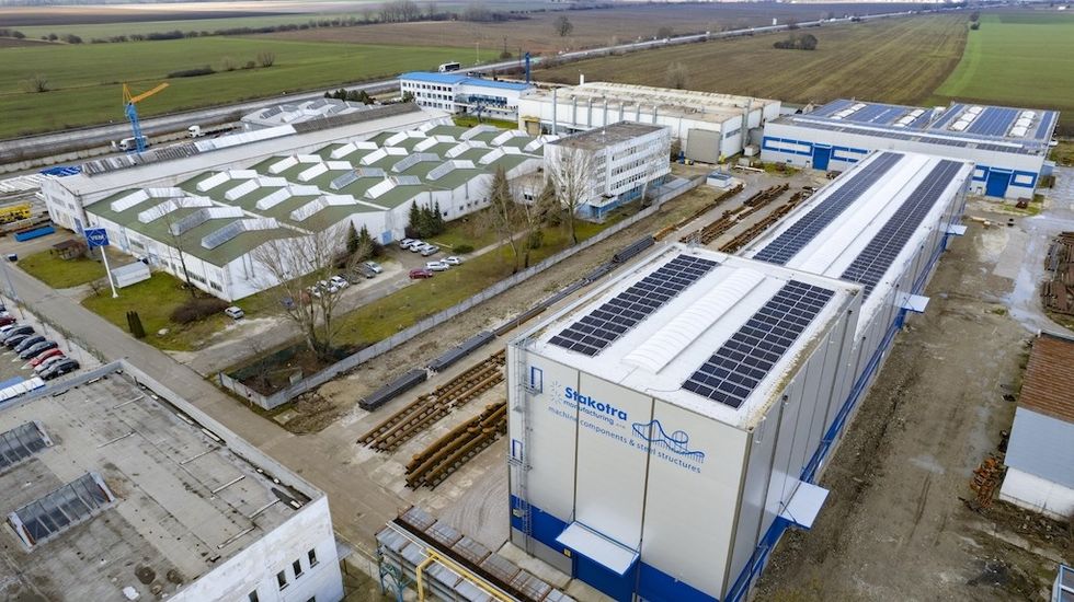 Aerial view of an industrial complex with solar panels on the rooftops.