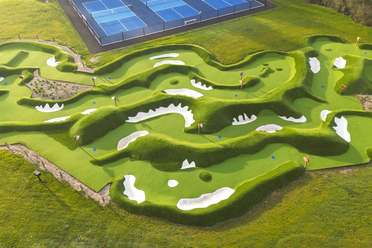 Aerial view of an intricately designed mini-golf course next to tennis courts.