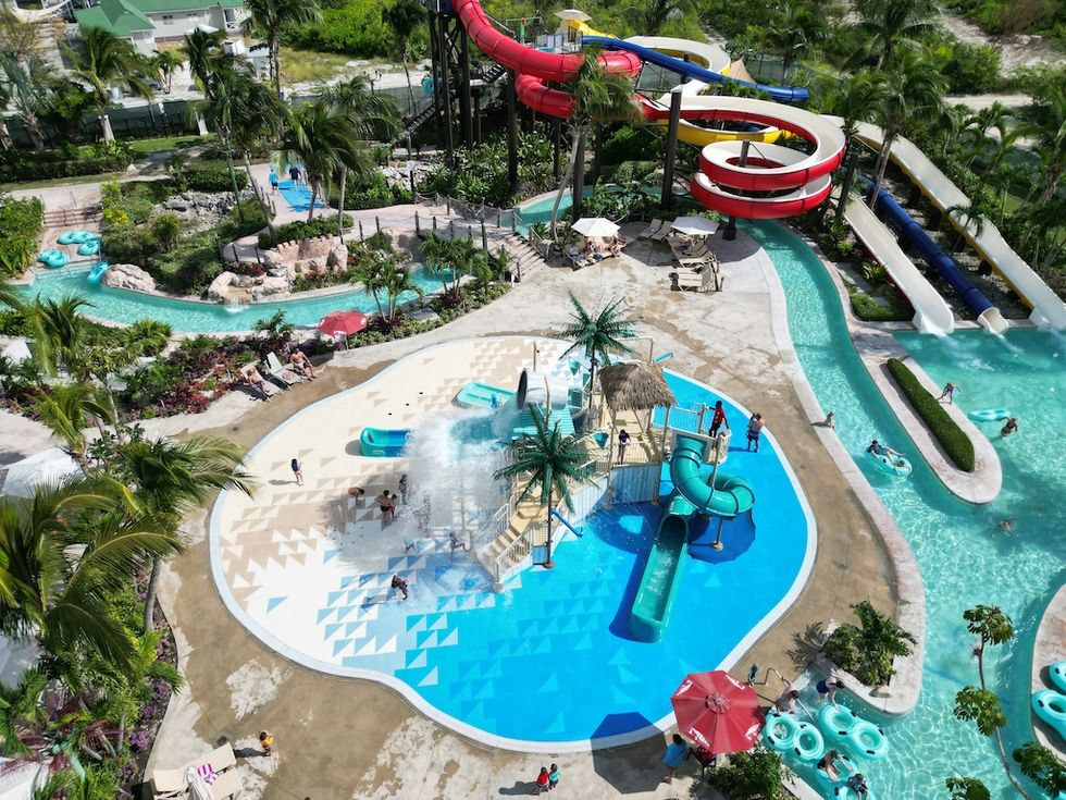 Aerial view of colorful water park with slides, lazy river, and palm trees.