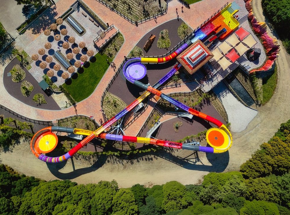 Aerial view of colorful water slides and a shaded seating area in a park.