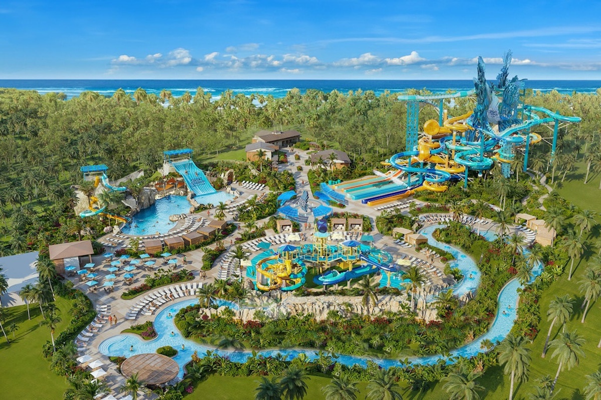 Aerial view of Great Tides Waterpark, a tropical water park with slides, pools, and lush greenery by the ocean, from Norwegian Cruise Lines