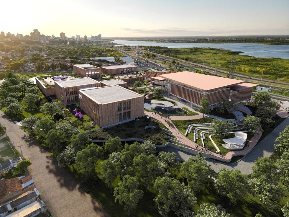 Aerial view of modern, spacious building complex with greenery and river in the background.