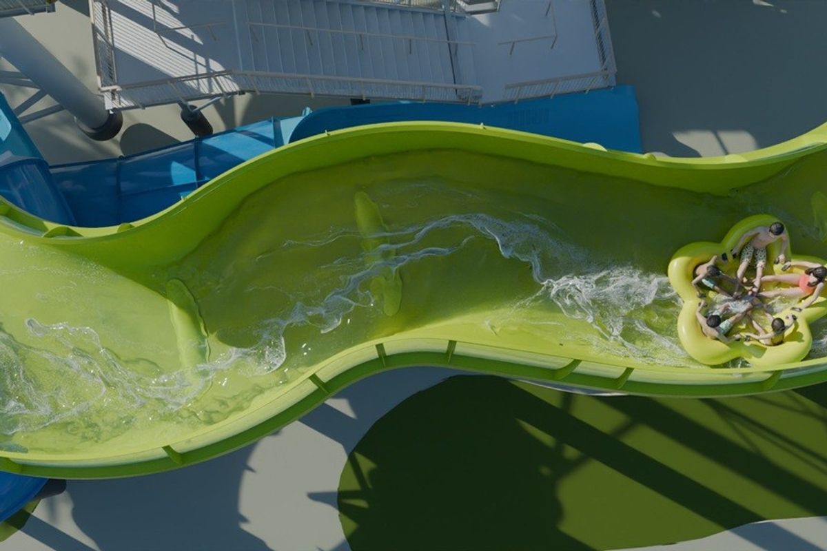 Aerial view of people on a green water slide in a circular raft.