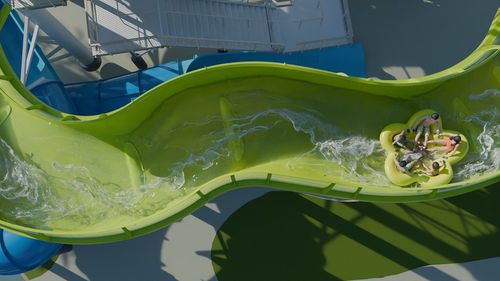 Aerial view of people on a green water slide in a circular raft.
