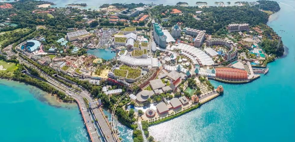 Aerial view of Sentosa Island, Singapore, with resorts, parks, and surrounding waters.