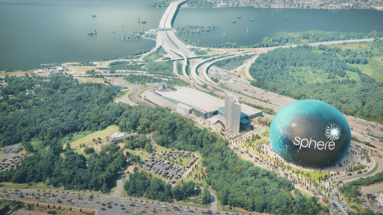 Aerial view of the Sphere venue beside a highway, surrounded by trees and a bay in Maryland.