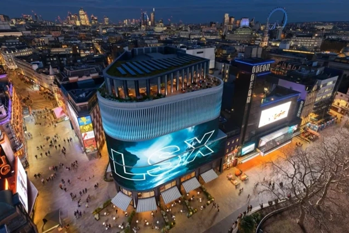 Aerial view of vibrant Leicester Square, London, lit up at dusk with bustling streets below.