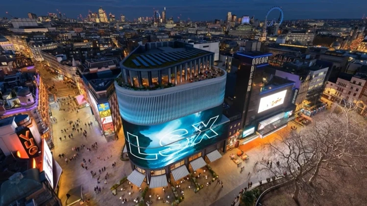 Aerial view of vibrant Leicester Square, London, lit up at dusk with bustling streets below.