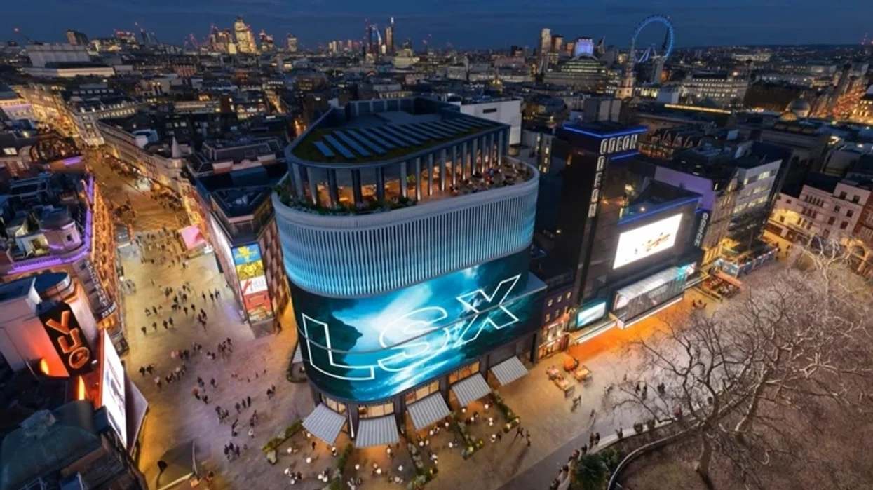Aerial view of vibrant Leicester Square, London, lit up at dusk with bustling streets below.