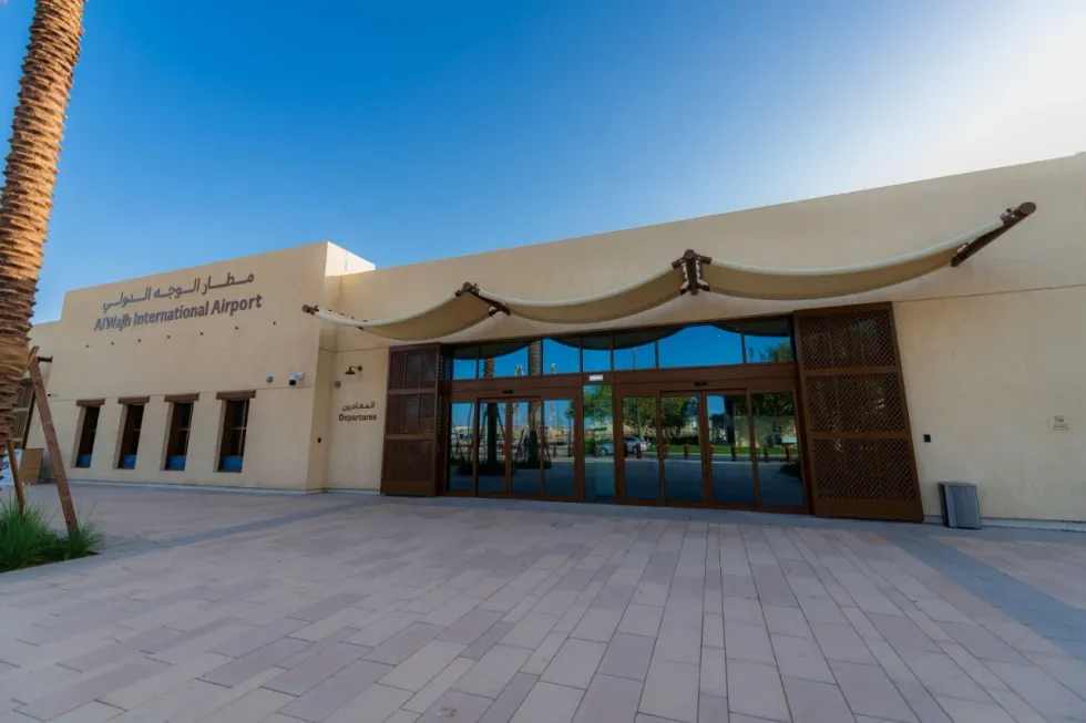 Al Wajh International Airport entrance under a clear blue sky.